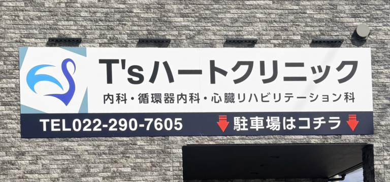 Sign for T's Heart Clinic on a brick wall, showing the phone number 022-290-7605 and parking directions in Japanese.